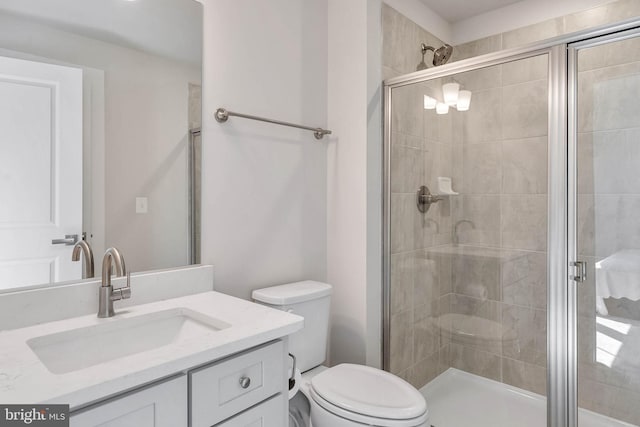 bathroom with a shower with door, vanity, and toilet