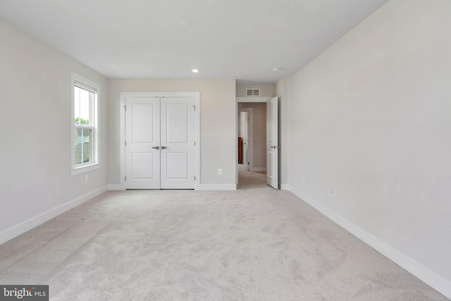 unfurnished bedroom featuring light colored carpet and a closet