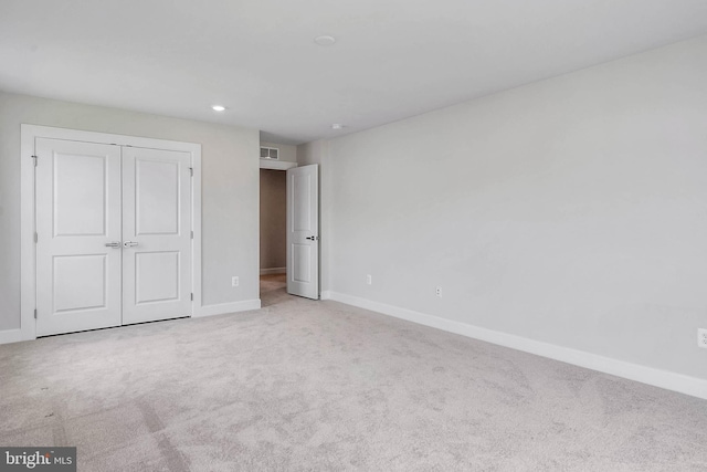 unfurnished bedroom with light colored carpet and a closet