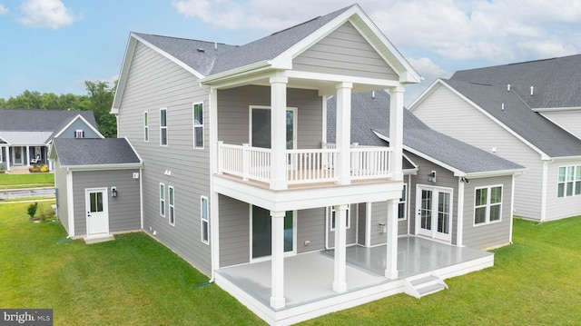 rear view of property featuring a patio, a lawn, french doors, and a balcony