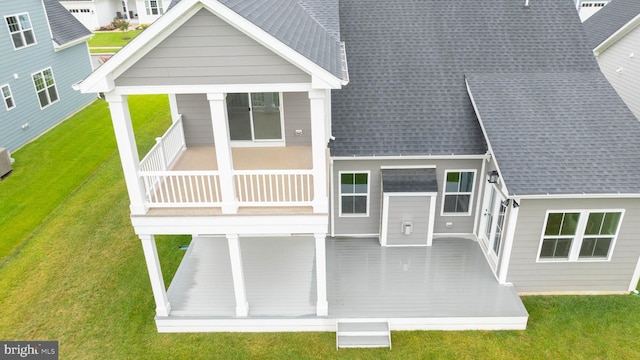 back of property featuring a balcony and a lawn