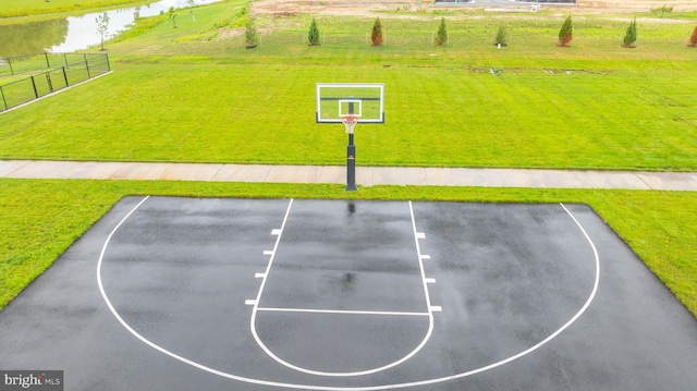 view of basketball court with a water view and a yard