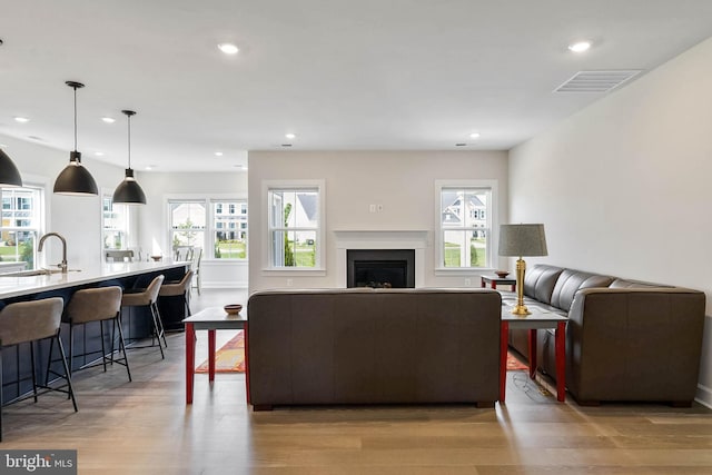 living room with plenty of natural light, sink, and light wood-type flooring