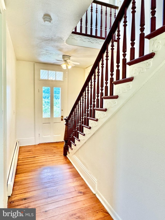 interior space featuring a textured ceiling, hardwood / wood-style floors, a baseboard radiator, and ceiling fan