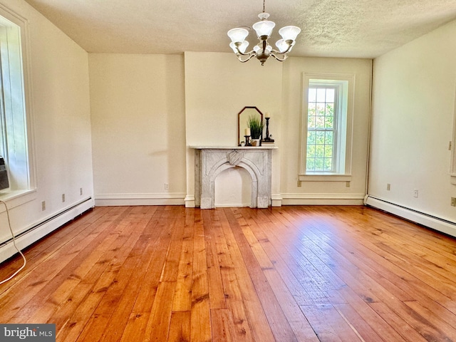 unfurnished living room with a textured ceiling, a premium fireplace, a notable chandelier, and light hardwood / wood-style floors