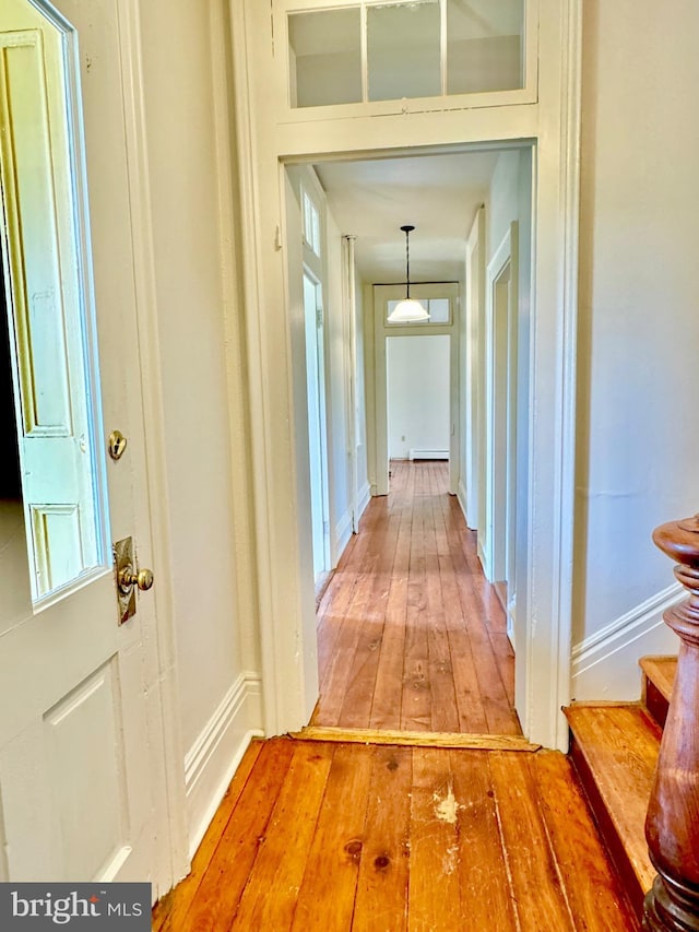 hall featuring baseboards, light wood-style flooring, baseboard heating, and stairs