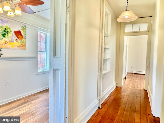 hall with baseboards, baseboard heating, and hardwood / wood-style floors