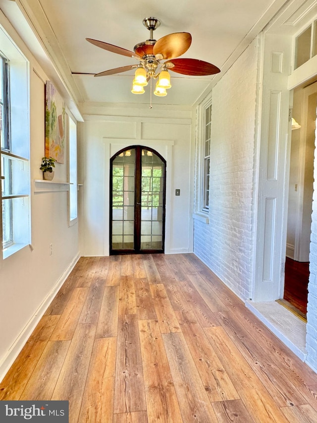 entrance foyer with brick wall, ceiling fan, light hardwood / wood-style floors, and french doors