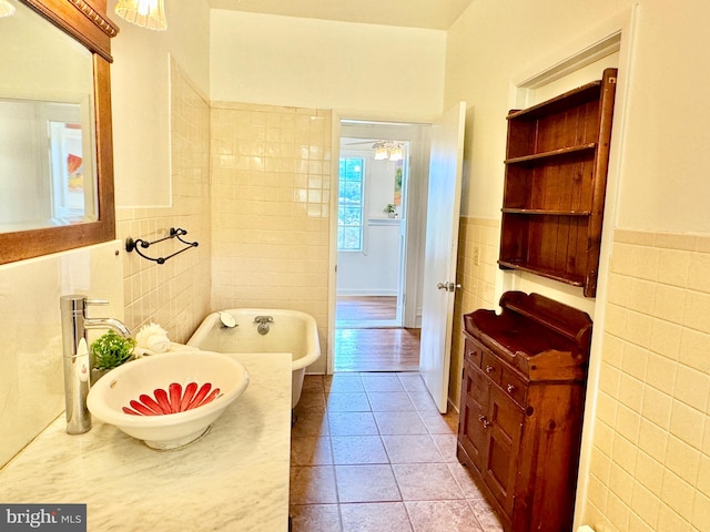 bathroom featuring a tub to relax in, vanity, tile walls, and tile patterned flooring