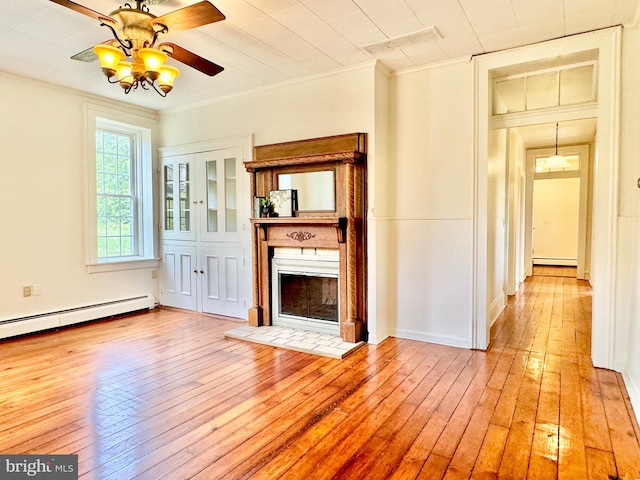 unfurnished living room with crown molding, baseboard heating, light hardwood / wood-style flooring, and ceiling fan