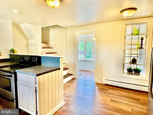 kitchen featuring stainless steel range with electric stovetop, a baseboard heating unit, light hardwood / wood-style flooring, and ceiling fan