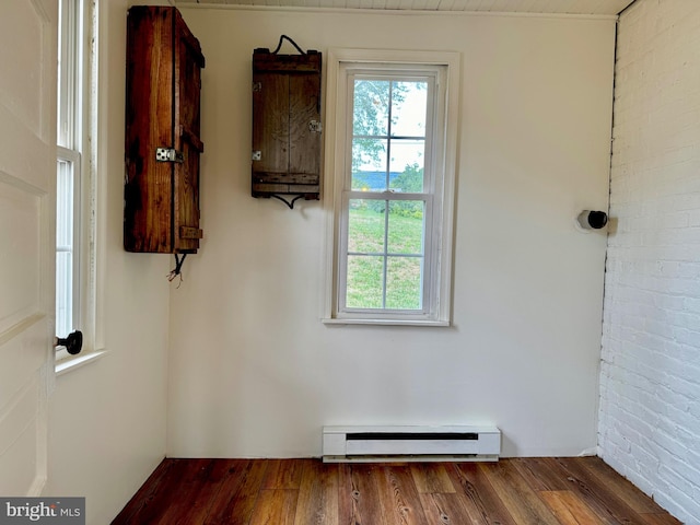 interior space featuring a wealth of natural light, baseboard heating, and wood-type flooring