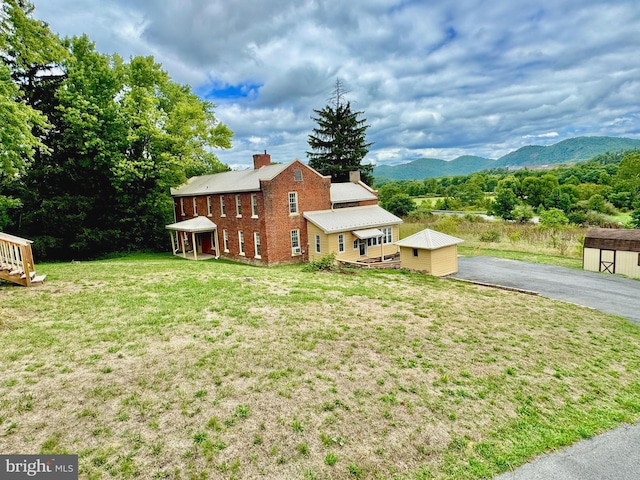 view of front of property with a mountain view, a storage shed, and a front lawn