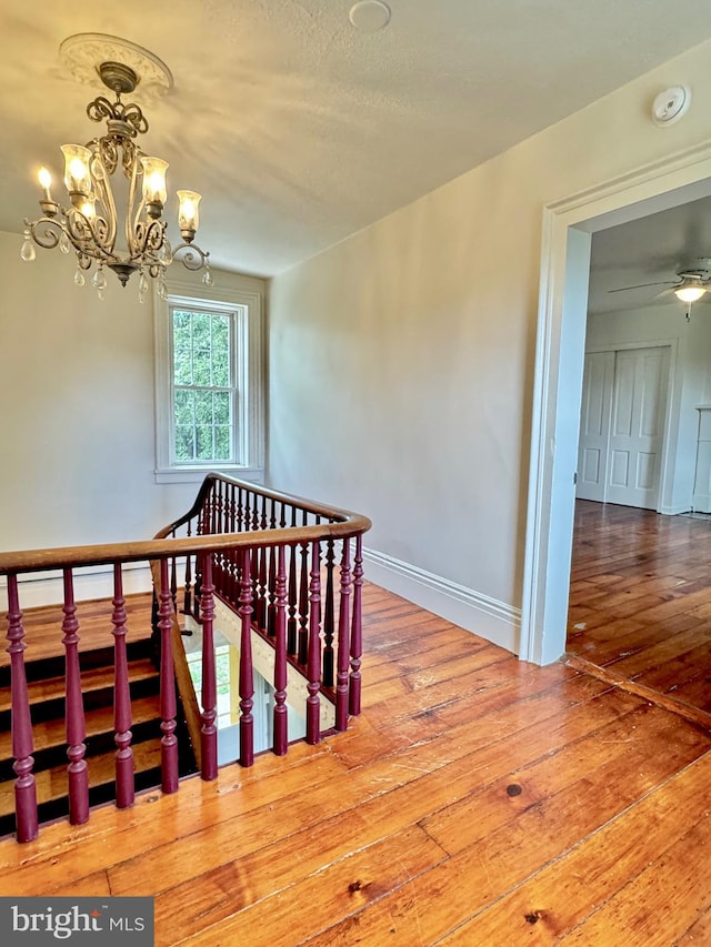 stairway featuring hardwood / wood-style flooring and an inviting chandelier