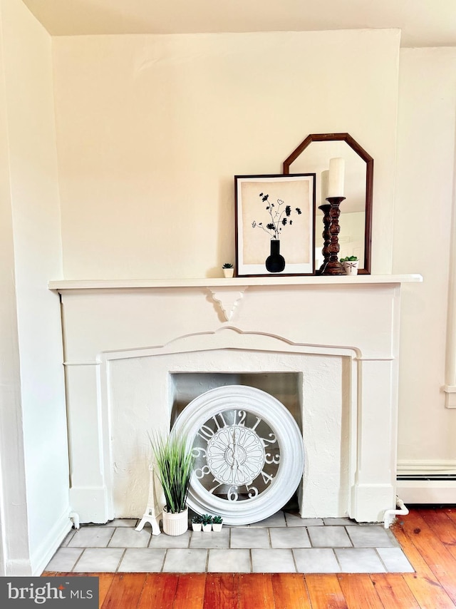 details with a baseboard heating unit, wood finished floors, and a fireplace with flush hearth