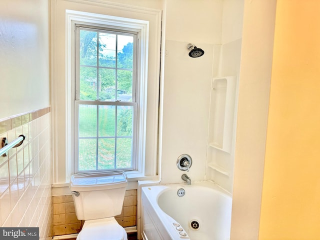 bathroom with tile walls, toilet, a wealth of natural light, and shower / washtub combination