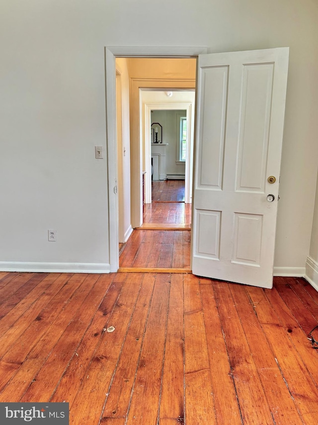 unfurnished room with baseboards, baseboard heating, and hardwood / wood-style floors