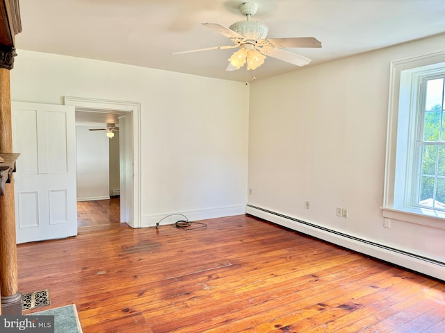 empty room with a baseboard heating unit, hardwood / wood-style flooring, and ceiling fan