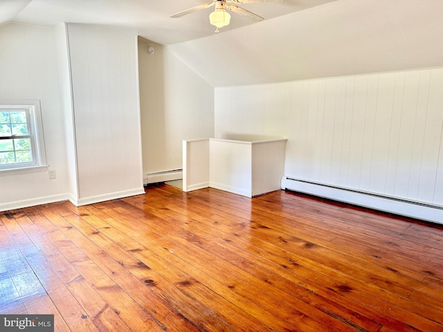 additional living space featuring lofted ceiling, light hardwood / wood-style flooring, ceiling fan, and a baseboard heating unit