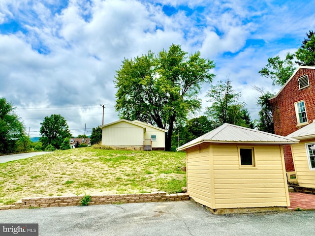 view of side of property with a yard and a shed