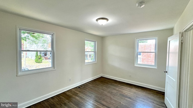 spare room featuring dark wood-type flooring and plenty of natural light