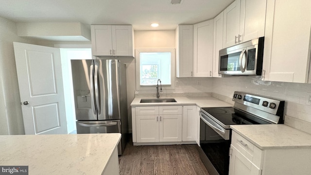 kitchen with appliances with stainless steel finishes, white cabinetry, sink, backsplash, and dark hardwood / wood-style floors