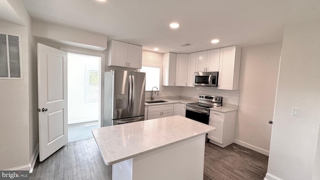 kitchen with a kitchen island, sink, dark wood-type flooring, appliances with stainless steel finishes, and white cabinets