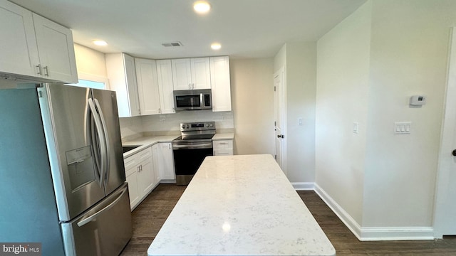 kitchen with dark wood-type flooring, white cabinetry, appliances with stainless steel finishes, and a kitchen island