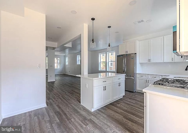 kitchen featuring a kitchen island, white cabinetry, hanging light fixtures, dark hardwood / wood-style floors, and stainless steel refrigerator