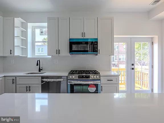 kitchen featuring white cabinetry, appliances with stainless steel finishes, backsplash, french doors, and sink