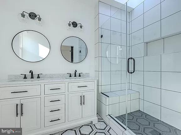 bathroom with an enclosed shower, vanity, and tile patterned flooring