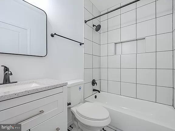 full bathroom with toilet, tiled shower / bath, and vanity