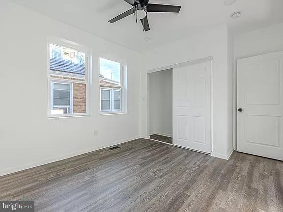 unfurnished bedroom featuring ceiling fan, a closet, and dark wood-type flooring