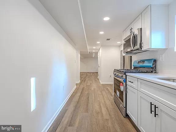 kitchen featuring white cabinets, appliances with stainless steel finishes, and light wood-type flooring