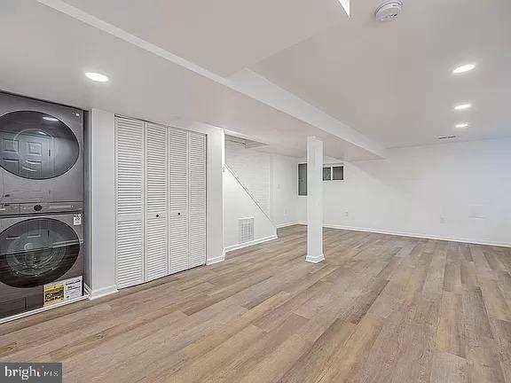 basement featuring light hardwood / wood-style floors and stacked washer / drying machine