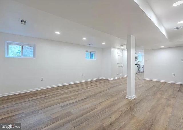 basement with plenty of natural light and light hardwood / wood-style flooring