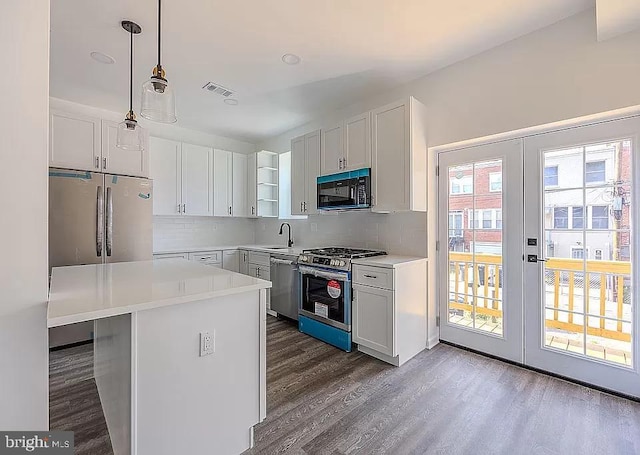 kitchen featuring stainless steel appliances, tasteful backsplash, decorative light fixtures, white cabinets, and sink