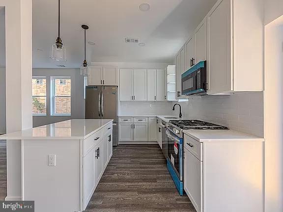 kitchen featuring decorative light fixtures, white cabinets, decorative backsplash, and stainless steel appliances