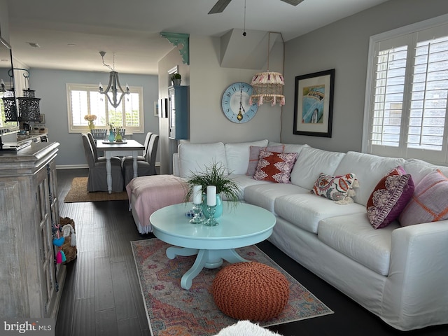 living room with ceiling fan with notable chandelier and dark hardwood / wood-style flooring