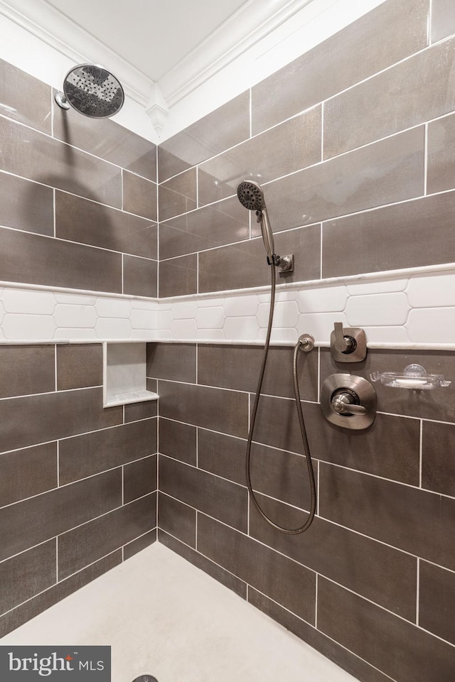 bathroom featuring a tile shower and ornamental molding