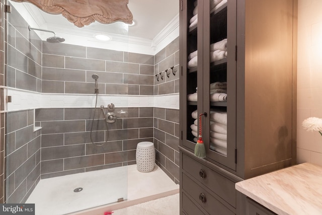 bathroom featuring tile walls, crown molding, and a tile shower