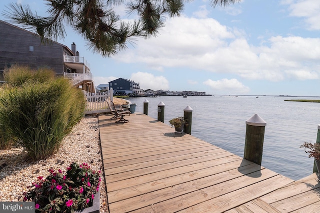 view of dock with a balcony and a water view