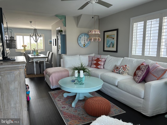 living room with ceiling fan with notable chandelier and dark hardwood / wood-style floors