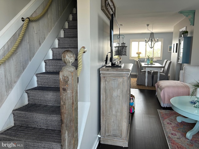 staircase featuring hardwood / wood-style flooring and a notable chandelier