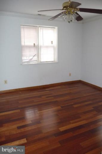 empty room with ornamental molding, wood-type flooring, and ceiling fan