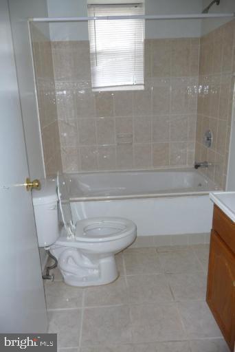 full bathroom featuring vanity, toilet, tiled shower / bath, and tile patterned flooring