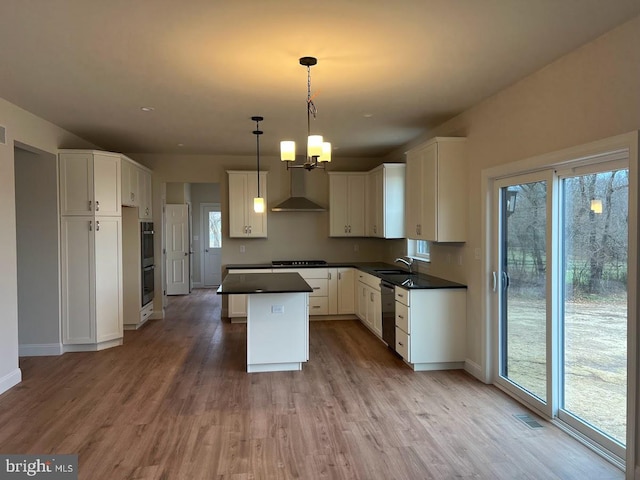 kitchen featuring wall chimney range hood, white cabinetry, wood-type flooring, and a wealth of natural light