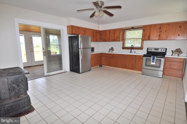 kitchen featuring light tile patterned flooring, appliances with stainless steel finishes, sink, backsplash, and ceiling fan