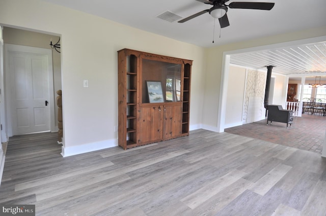 interior space with ceiling fan, light hardwood / wood-style flooring, and a wood stove