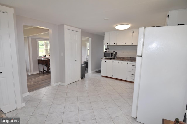 kitchen with white refrigerator, light tile patterned floors, and white cabinets